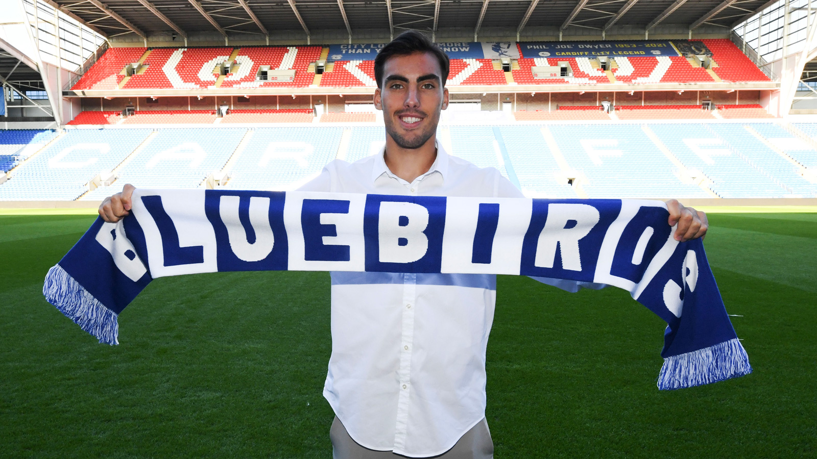 The player holds up a City flag at Cardiff City Stadium...